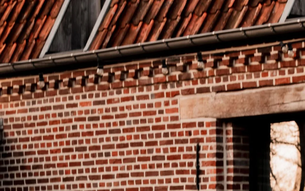 Bakstenen gevel van een oude hoeve in avondlicht